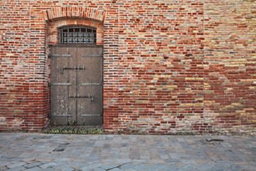 old brick wall, stone paved sidewalk and ancient wooden door