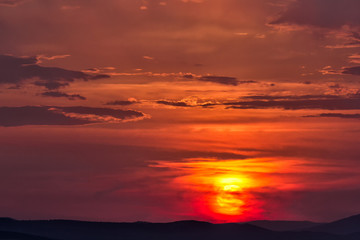 Cloudy colorful sunset with a big sun over the hills, Enisala, Dobrogea, Romania