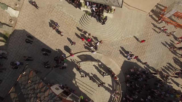 4k Crowd of people move at old European piazza center from above. Sun day group of guests stand at church stairs greeting meeting waiting low aerial drone shot. Life of small medieval town in Italy