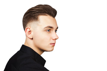 Young white guy with a pompadour hairstyle dressed in black shirt with a serious face looking aside isolated on white background.