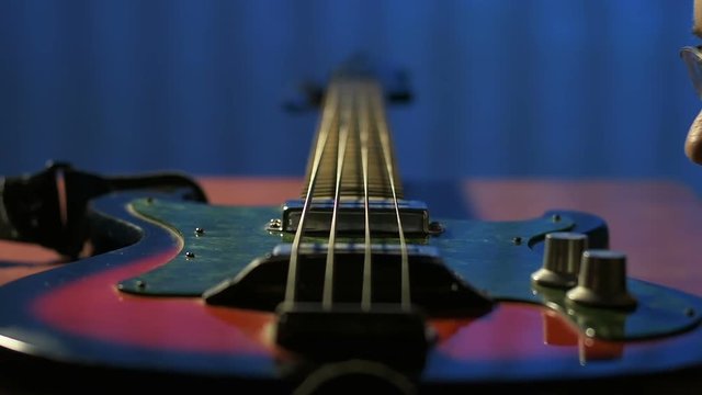 Guitarist blows away dust from his old bass guitar in attic