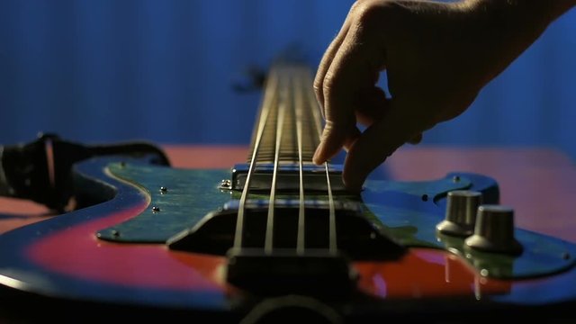 Guitarist tries to play his old bass guitar closeup