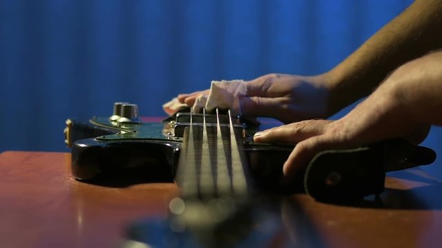Luthier carefully wipes case of bass guitar after repair