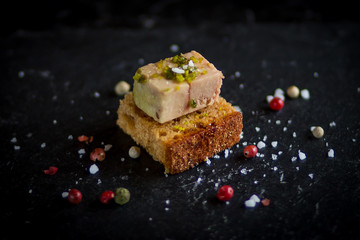 isolated foie gras toast on black plate with sea salt sprinkles - obrazy, fototapety, plakaty