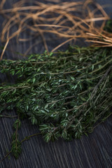 Bunch of thyme tied with straw rope on grey wooden background.
