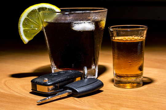 Car keys laid on the bar beside cocktail and whiskey. Whiskey and cocktail at the bar. Alcoholic glasses and car keys. Do not drink alcohol while driving.
