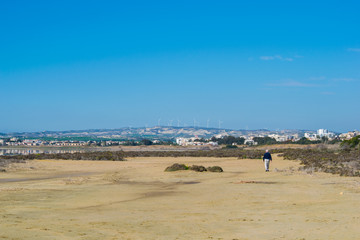 old man walking on sand