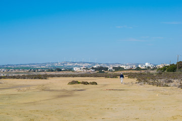 old man walking on sand