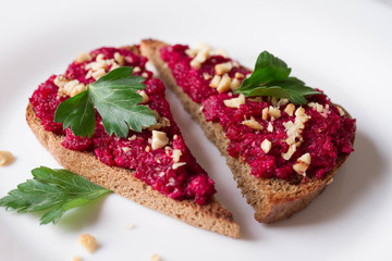 Homemade toast from whole grain bread with beet paste, greens and nuts.  Useful dietary baking. Beet hummus. Healthy food for vegan
