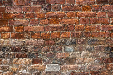 An old weathered, damaged, badly repaired red brick wall full frame