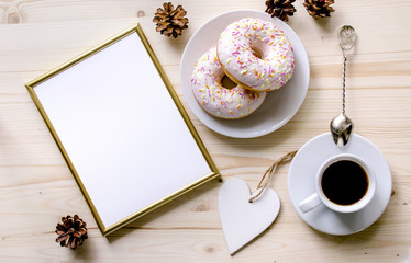 Morning composition with coffee and donuts  on a wooden table. Gold frame for the presentation of works or text. Top view. Copy space. Mock-up