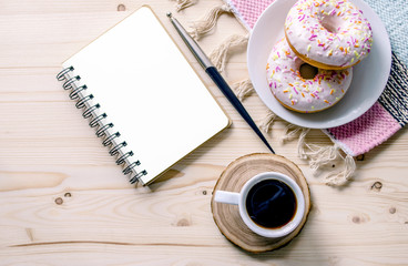 Morning composition with coffee and donuts  on a wooden table.. To-do list. Office table desk. Home office workplace. Top view. Copy space. Mock-up