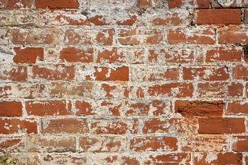 An old weathered, damaged, formerly painted, badly repaired red brick wall full frame background