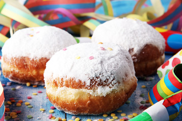 German donuts with jam and icing sugar. Carnival powdered sugar raised donuts with paper streamers.