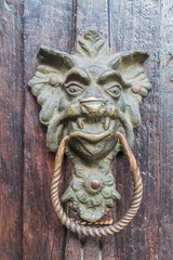 Isolated, close up of aged wooden door with decorative handle on a dragon head knocker, and other architectural details - 191673730