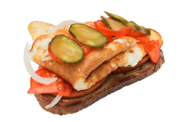 A sandwich with sausage, scrambled eggs, onions, pickles and tomatoes.
