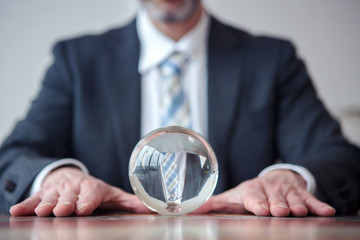businessman looking at glass ball on table