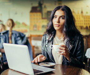 Young pretty spanish woman in cafe in city centre with tablet laptop