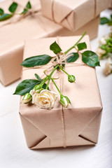 Gift boxes with branch of fresh roses with leaves on wooden table, copy space. Holiday background, sale, shopping. Greeting card for Valentines Day, Womens Day, Mothers Day, birthday, Easter, flat lay