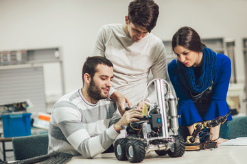 Young students of robotics preparing robot for testing in workshop