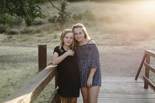Portrait of sisters standing on wooden bridge