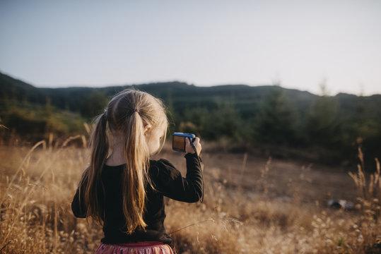 Girl with pigtails photographing while standing on field