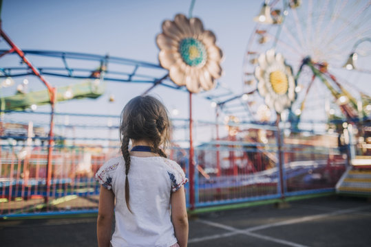 Rear view of girl with pigtails looking at amusement park rides