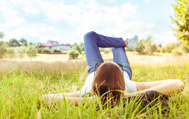 Relax in nature. Young woman lying on grass looking up into the sky. 
