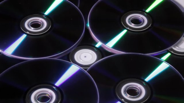 A bunch of shiny DVDs rotating. Dark shot.

