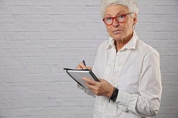 Portrait of beautiful senior woman writing something. Modern casual dressed older woman, lifestyle concept