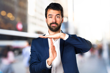 Handsome man making time out gesture on unfocused background