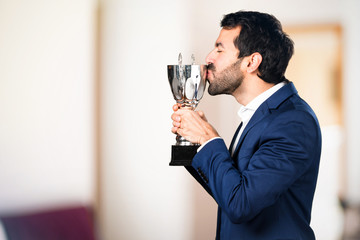 Handsome man holding a trophy on unfocused background