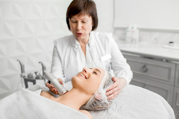 Obraz na płótnie Canvas Senior woman cosmetologist making facial procedure to a young client in a luxury medical resort office