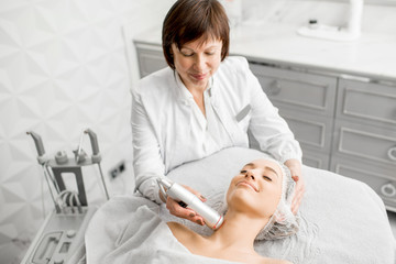 Senior woman cosmetologist making facial procedure to a young client in a luxury medical resort office