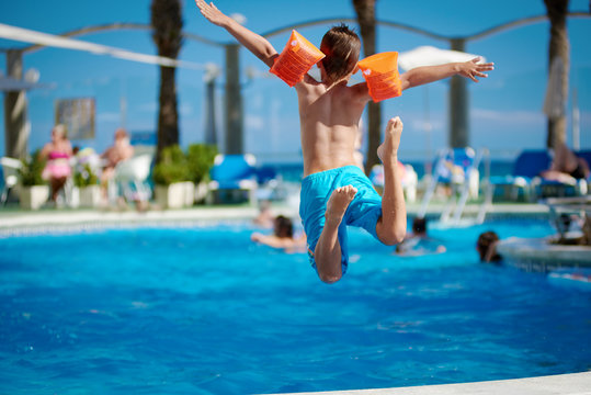 Caucasian boy jumping into the pool.