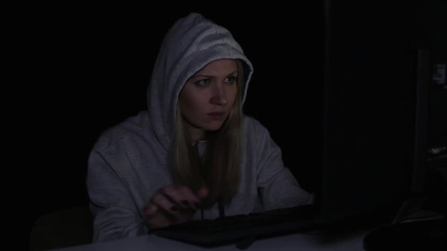 Woman hacker at the computer in the dark.