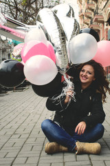 close-up portrait of a charming smiling girl with balloons against the background of an old beautiful city