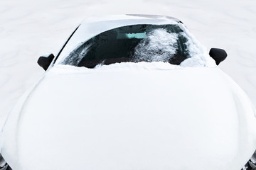 White car covered with white snow.