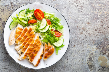 Healthy vegetable salad with grilled chicken breast, fresh lettuce, cherry tomatoes, red onion and pepper