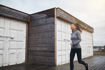 Fit young Asian woman jogging outside on an overcast day