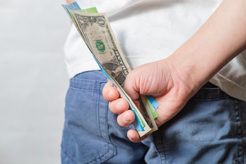 the child holds in his hand behind a money bill dollars and new rubles in a white shirt and blue pants