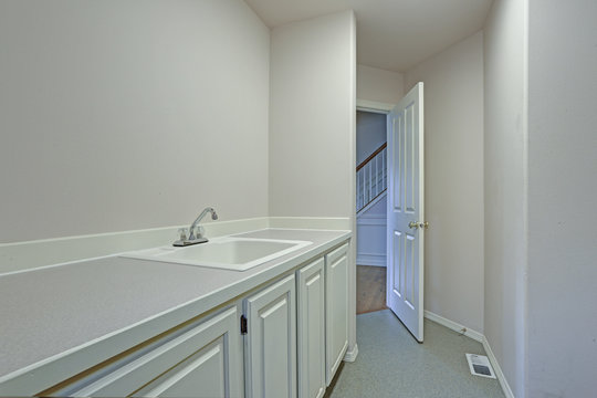Detail view of white laundry room with shaker cabinets.