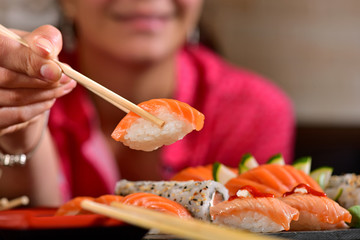 Woman's hand holding sushi on restaurant table