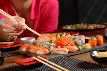Woman's hand holding sushi on restaurant table