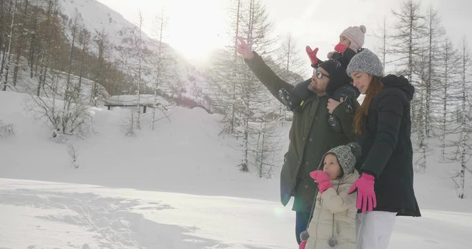 On a winter day, a family in the mountains walks in the snow and nature. Concept of: winter holidays, family, christmas, mountain