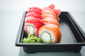 Beautiful rolls in black container on white background with reflection, for a menu or website