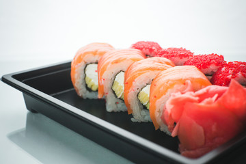 Beautiful rolls in black container on white background with reflection, for a menu or website