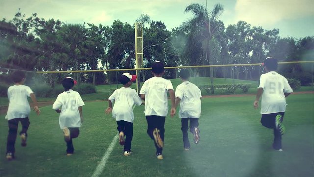 Slow motion from behind of kids running during baseball practice