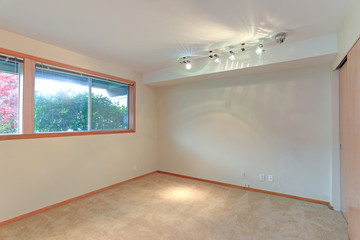 Empty room interior features white walls and beige carpet floor.