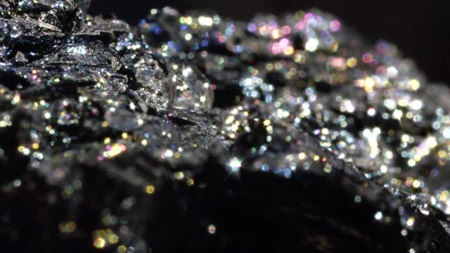 BOKEH CLOSE UP Extremely detailed piece of Hematite mineral sparkling under light. Radiant iron oxide shimmering in a spectrum of color. Inexpensive metallic crystal used for jewelry in Victorian era